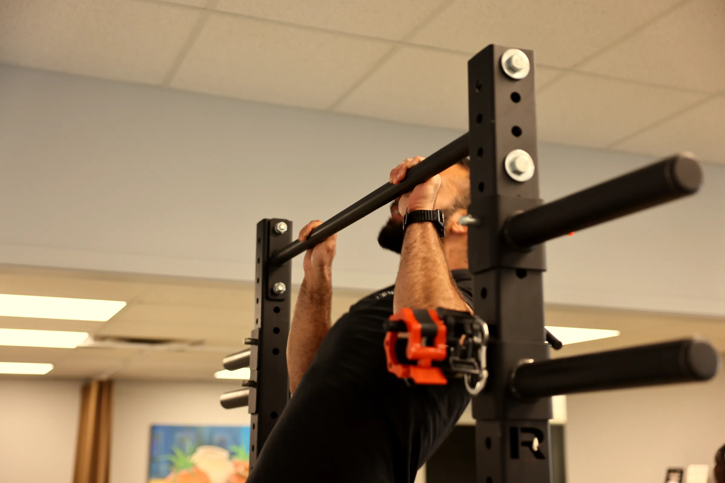 Person doing a pull-up on the rack bar at the clinic.